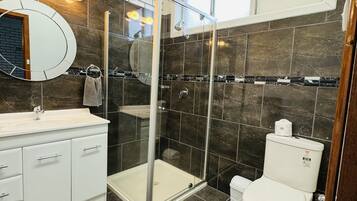 A modern bathroom with a glass-enclosed shower, a white sink, and a toilet.