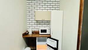 Una cocina compacta equipada con microondas, refrigerador y contenedor de basura.