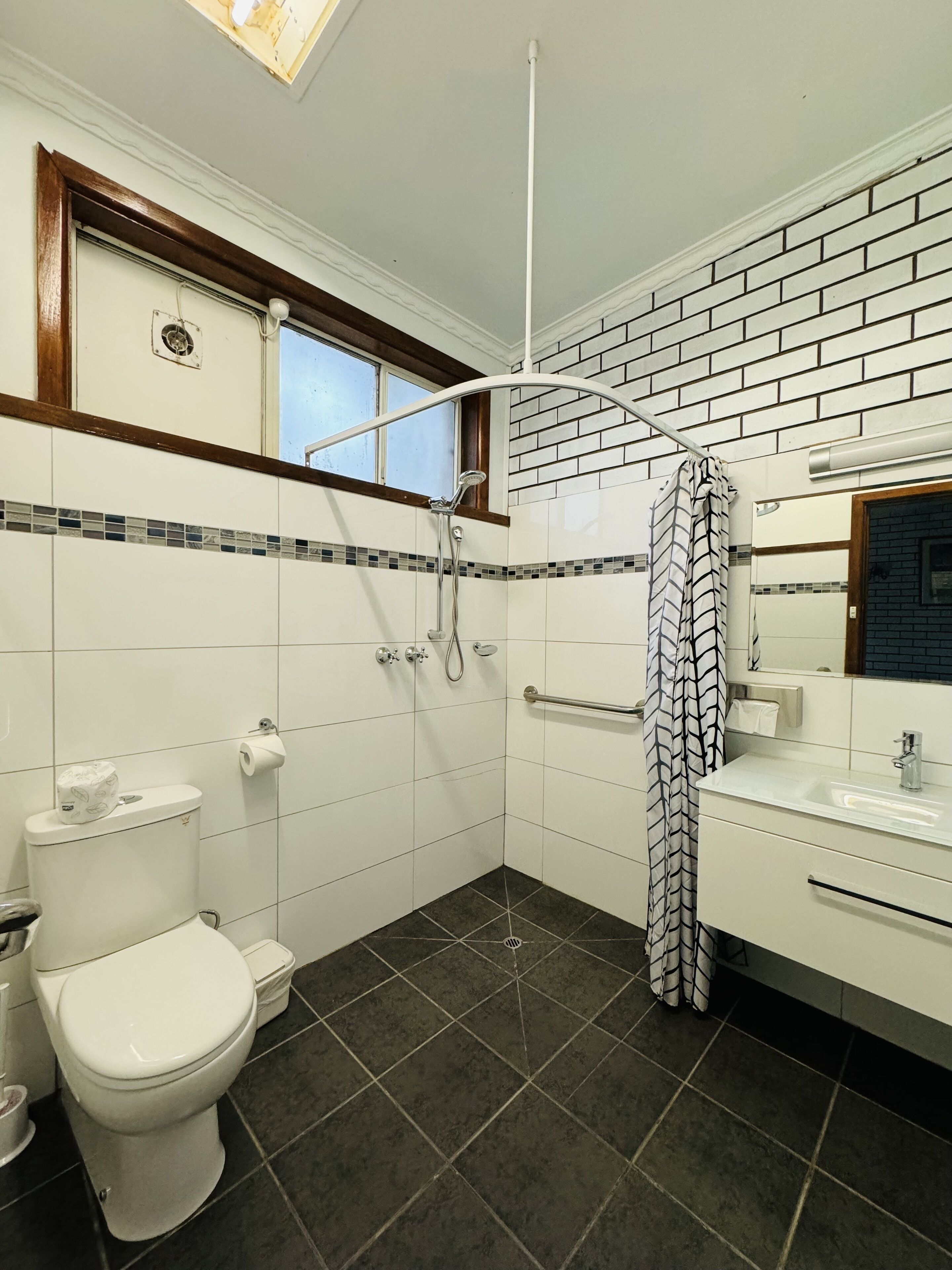 A bathroom with a toilet, shower, and sink.