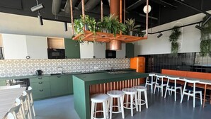 Une cuisine moderne avec des meubles de couleur verte, un îlot central doté de tabourets et des plantes suspendues.