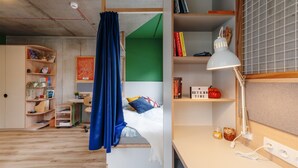 Une petite pièce comprenant un lit, un bureau et une bibliothèque.