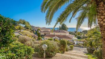 A residential area with houses, a clear sky, and a view of the sea.