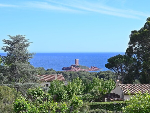 Vista costera con una torre, casas y abundante vegetación.