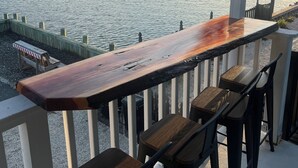 A wooden bar with two chairs, overlooking a body of water with a distant shoreline. - Sunset Cove: Bayview, fantastic location, close to everything (Long Beach)