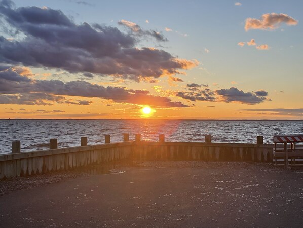 A sunset over a body of water with a wooden pier and a bench. - Sunset Cove: Bayview, fantastic location, close to everything (Long Beach)