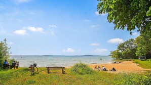 A beach with a wooden bench, a bicycle, and people relaxing on the sand. - Amazing apartment in Klink with WiFi (Klink)