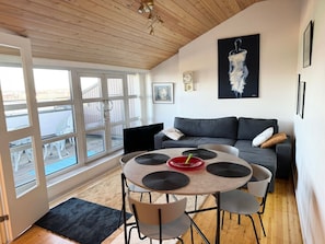 A modern living room with a round table, grey sofa, and large windows.