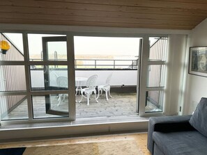 A room with a sliding glass door leading to an outdoor patio with white chairs and a table. - Crown of Kruununhaka with view (Helsinki)