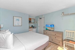 Ein Schlafzimmer mit Bett, Kommode, Fernseher und Stuhl.