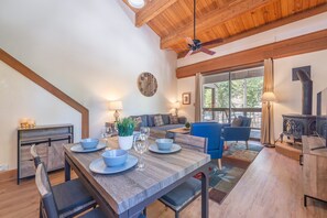 A dining area with a wooden table set for four, a blue sofa, and a fireplace. - Aspen Escape~Walk to Northstar Slopes (Truckee)