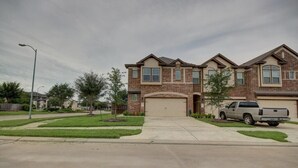 A two-story residential building with a brick facade, a garage, and a driveway. - Roseberg/Suglarland  3-BR - Extended Stay 30 days  (Rosenberg)