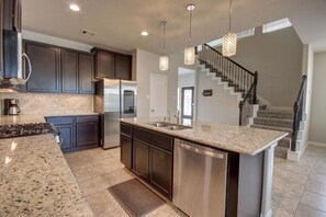 A modern kitchen with granite countertops, stainless steel appliances, and dark cabinetry. - Roseberg/Suglarland  3-BR - Extended Stay 30 days  (Rosenberg)