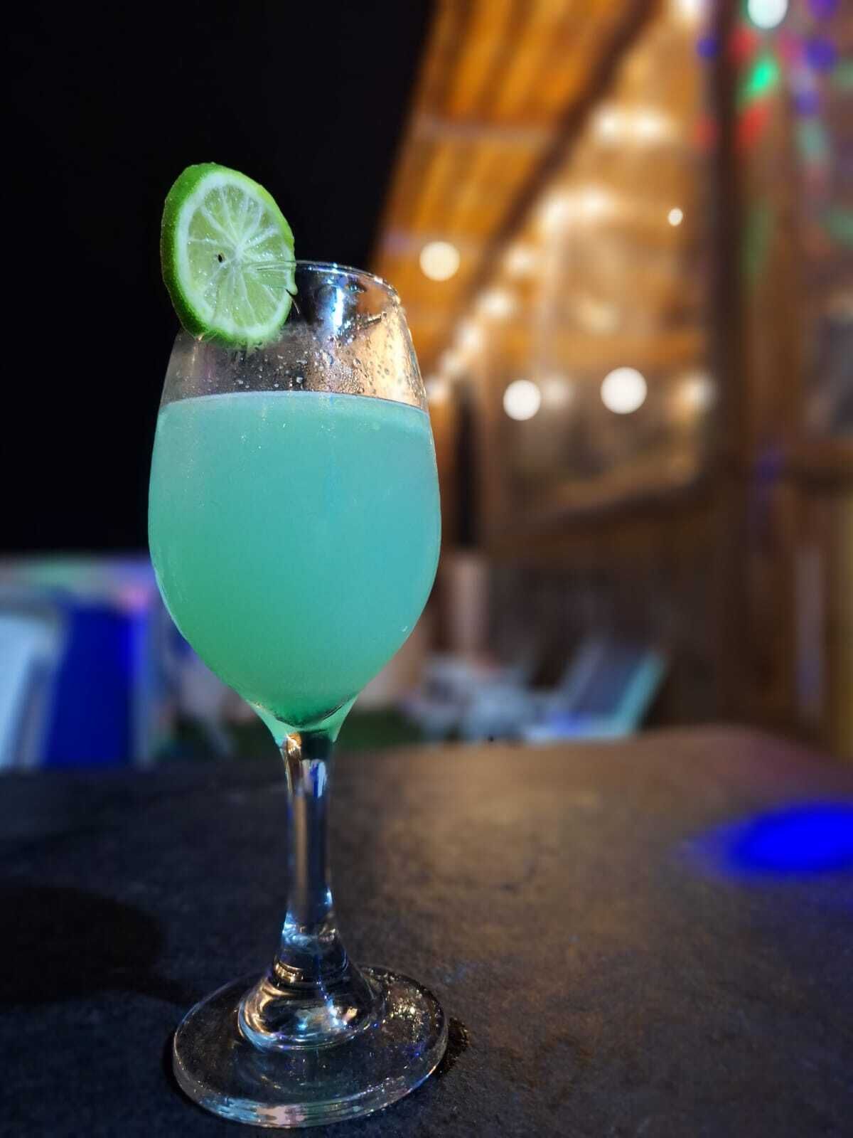 A cocktail in a glass with a lime garnish, placed on a table.