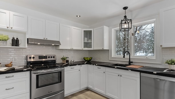 A modern kitchen with white cabinets, stainless steel appliances, and a black countertop. - Balsam Retreat- Muskoka Getaway
Pet Friendly (Huntsville)
