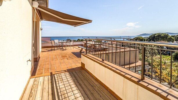 A balcony with a view of the sea, a table with chairs, and a wooden deck. - Sant Genis 19.2 Top floor apartment with terrace (Llança)