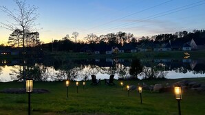 A serene lakeside view at dusk with a row of evenly spaced street lamps along the water's edge.