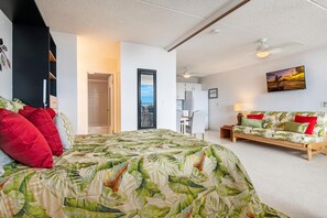 A bedroom with a bed, a sofa, a desk, and a view of the outside.