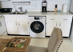 A compact kitchen with a washing machine, a coffee maker, and a sink.