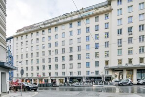 Um hotel com vários andares, fachada uniforme, várias janelas e um restaurante no nível da rua.