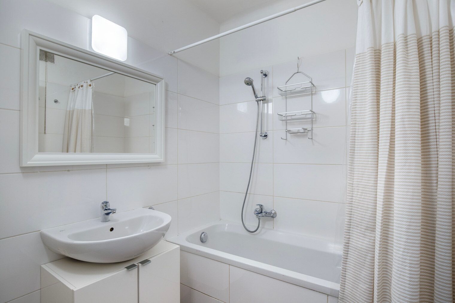 A modern bathroom with a white sink, a bathtub, and a shower.