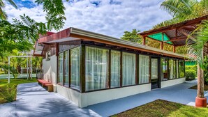 Un bâtiment moderne doté de grandes fenêtres en verre, d’un chemin en béton et d’un petit espace jardin.