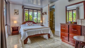 A bedroom with a bed, wooden dresser, and a bathroom door. - Beachfront Studio 3, Playa Palo Seco (Parrita)