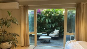 Una habitación con puerta corredera de vidrio que da a un patio con mesa, sillas y planta en maceta.