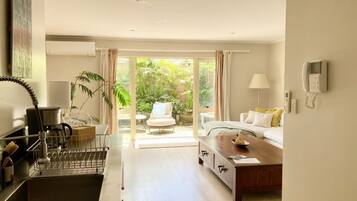 A modern hotel room with a kitchen area, a dining table, and a sofa.