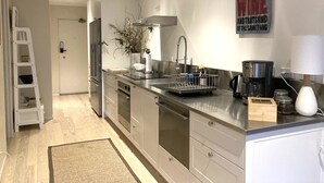 Una cocina moderna con electrodomésticos de acero inoxidable, lavavajillas integrado y cafetera.