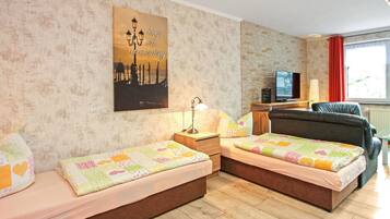 Ein Hotelzimmer mit zwei Betten, einem Fernseher, einer Lampe und einem Stadtplakat an der Wand.