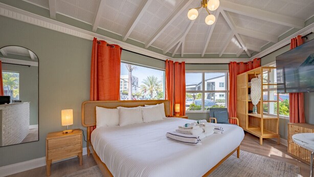 Un dormitorio espacioso con una cama grande, una mesita de noche de madera con una lámpara, un armario de madera y un ventanal con vistas al exterior.