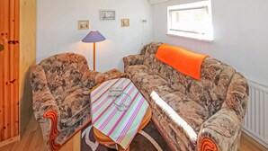 Una sala de estar con un sofá estampado, una mesa a rayas y una lámpara.