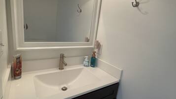 A bathroom with a white sink, dark cabinets, a mirror with two lights, and a towel rack.
