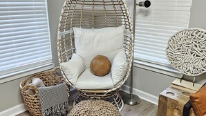 A room with a wicker chair, a floor lamp, and a decorative wall piece. - NEWLY RENOVATED 1100 Sq ft! Bungalow Retreat 5 minutes from Theme Park and Beach (Atlantic City)