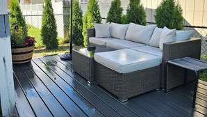A covered outdoor patio with a wicker sofa and a large umbrella. - NEWLY RENOVATED 1100 Sq ft! Bungalow Retreat 5 minutes from Theme Park and Beach (Atlantic City)