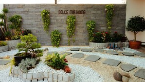 A garden area with a stone wall, potted plants, and stepping stones. - Dolce Mia Home Ninh Binh (Ninh Binh)