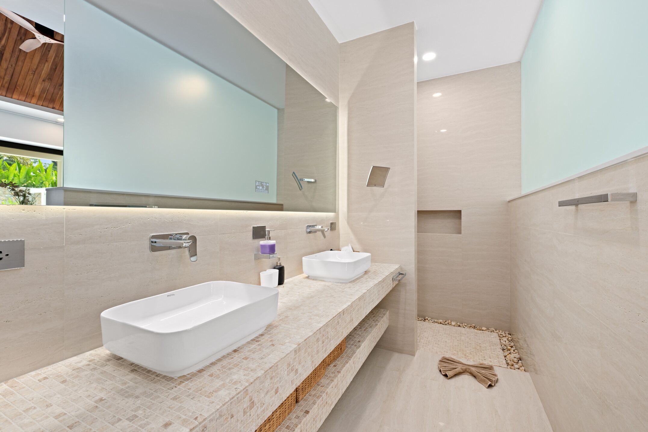 Un baño moderno con dos lavamanos, un espejo grande y una zona de ducha.