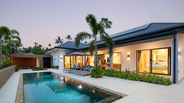 A modern resort with a swimming pool, lounge chairs, and a well-lit outdoor area. - Luxury Balinese Private Pool Villa-KBR12 (Koh Samui)