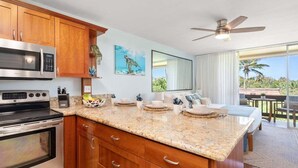 Een moderne keuken met granieten aanrechtbladen, roestvrijstalen apparatuur, houten kastjes en een groot eiland.