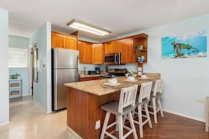 A kitchen with wooden cabinets, stainless steel appliances, and a granite countertop.
