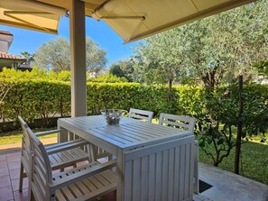 An outdoor patio with a table and chairs, surrounded by greenery and a clear sky. - Villa Roberta - Modern independent villa (Marina di Casal Velino)