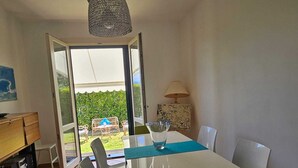A dining area with a white table, clear chairs, a glass pitcher, and a lamp.