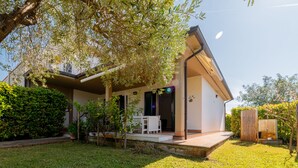 A modern house with a covered porch, a small garden, and a fenced backyard.