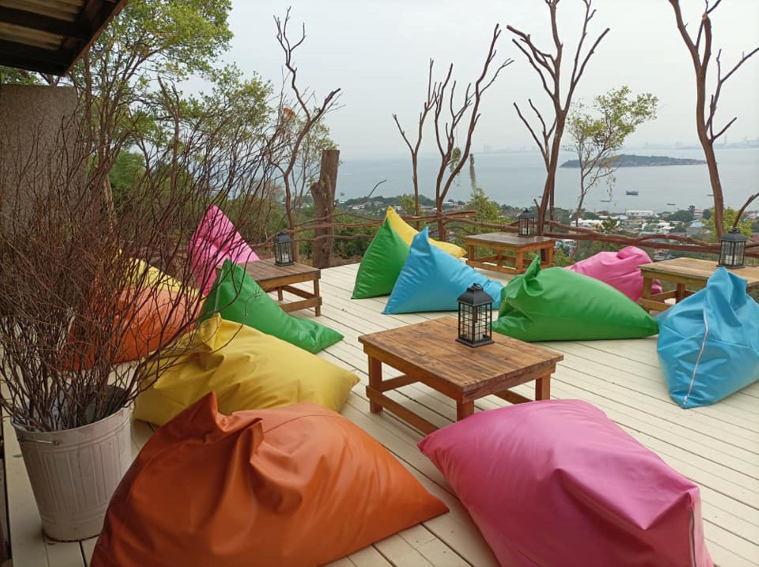 Een terras met kleurrijke zakkenstoelen, een lantaarn en uitzicht op zee.