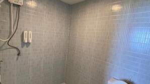 Pieni kylpyhuone, jossa on wc, suihku ja käsienkuivaaja.