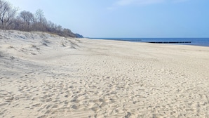 A sandy beach with a clear sky and a distant pier. - Beautiful home in Sarbinowo with WiFi (Sarbinowo)