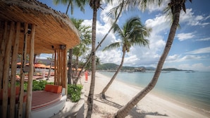 A beachside resort with a wooden gazebo, palm trees, and a view of the sea and distant mountains. - 79 Beach Club and Resort Samui (Koh Samui)