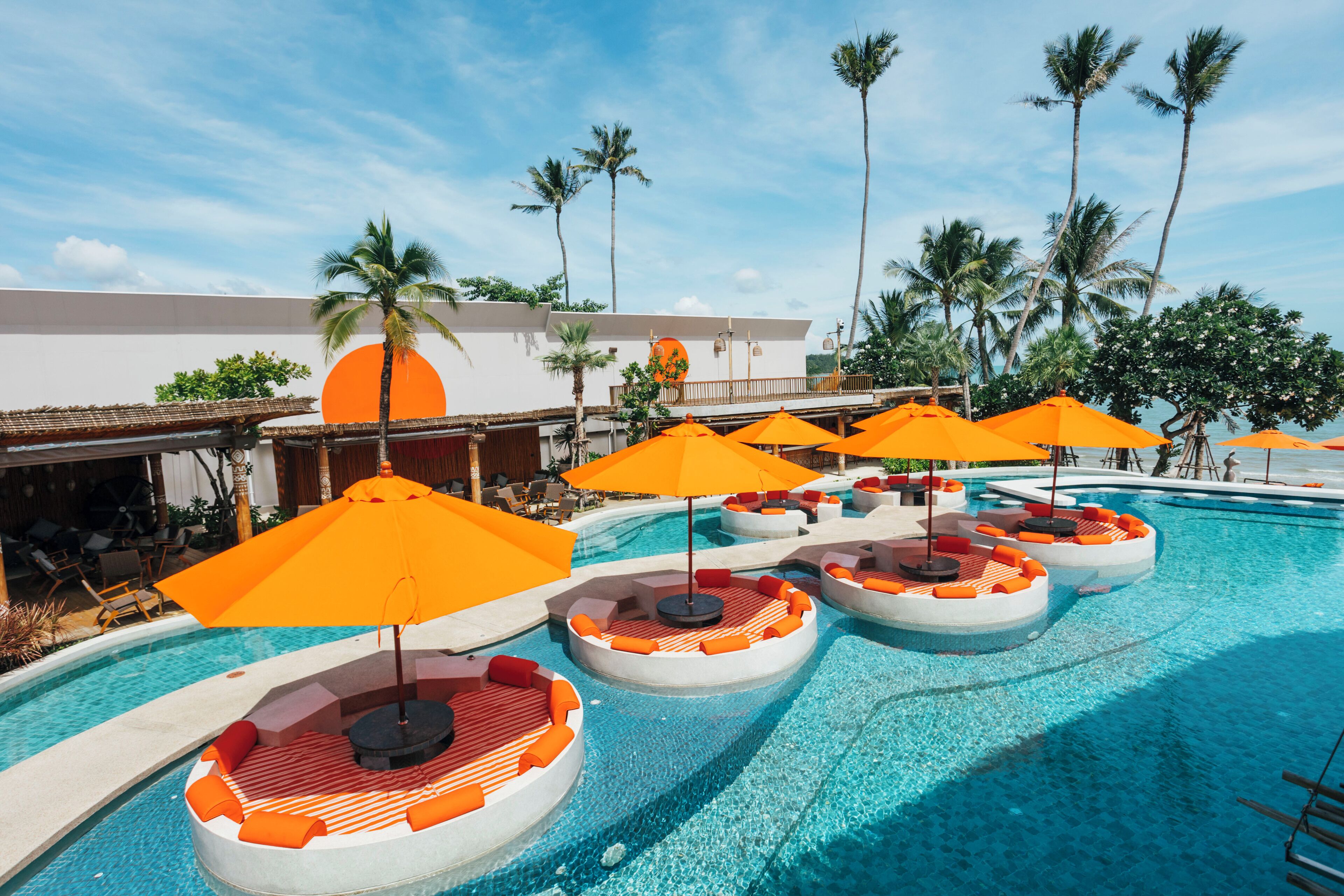 A pool area with circular seating and orange umbrellas.