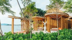 A beachside resort with bamboo structures, lush greenery, and a view of the sea. - 79 Beach Club and Resort Samui (Koh Samui)
