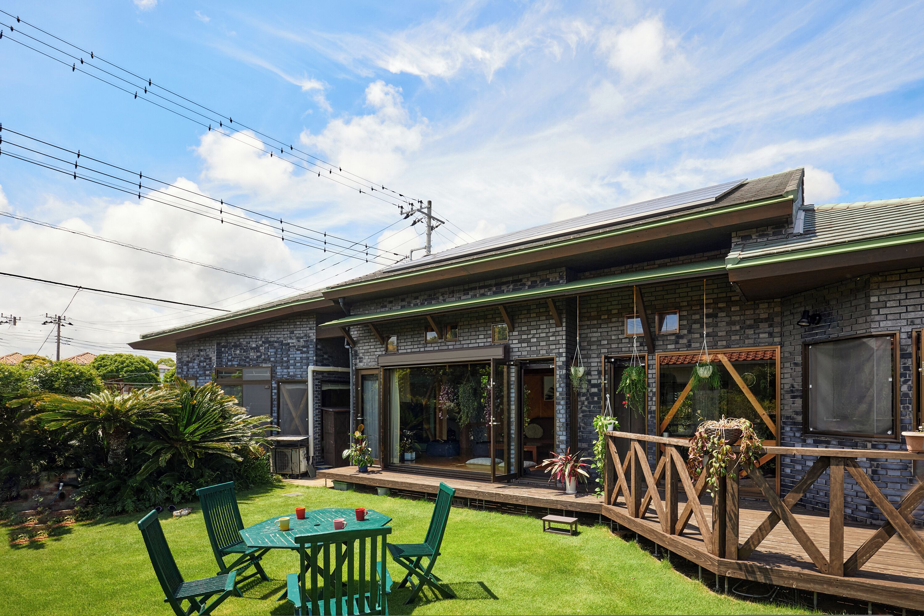 Een modern huis met een bakstenen gevel, grote glasramen en een houten terras.